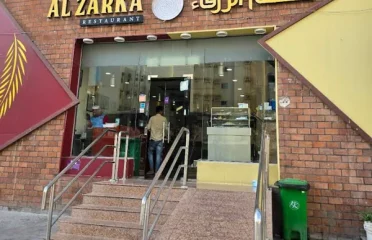 Restaurant storefront entrance with brick facade, Arabic and English signage, and glass doors at Al Zarka Restaurant.