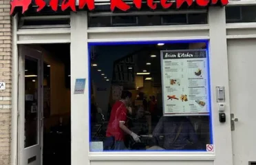 Asian restaurant storefront with red signage and a street-level window displaying the menu at The Asian Kitchen project.